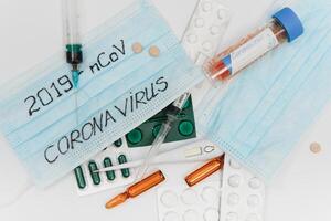 Surgical mask protective mask with CORONAVIRUS text. Virus 2019-n CoV in Wuhan, China. Tablets, mask, syringe photo