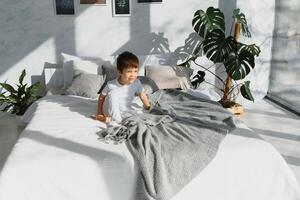 pequeño chico vistiendo blanco pijama en cama foto