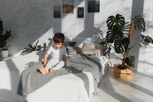 pequeño chico vistiendo blanco pijama en cama foto