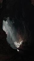 A cave with a stunning ray of light shining through a large hole in the ceiling video