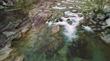 Drone view of rocky stream in mountain terrain. Fast water flows in rocky, stream captured from above. Explore nature through aerial footage of rocky stream. video