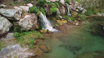 shows small waterfall, mountain river with crystal clear water. Capture of small waterfall, mountain river in serene environment. Scenic view of small waterfall and mountain river video
