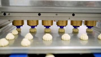 The cream is applied to the cookies. Cookie shop. Automatic application of cream to a confectionery product, close-up. photo