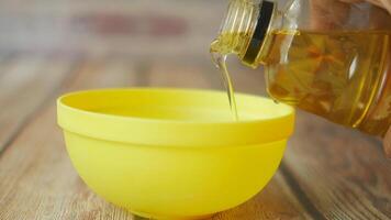 pouring sunflower oil in a yellow color bowl on table video
