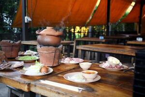 Jim Jum ,Thai Hot Pot with Clear Soup with Eggs, glass noodles, raw pork serve with Charcoal stove photo