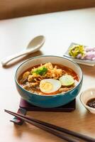 Northern Thai style curried noodle soup with beef and egg on wooden table photo