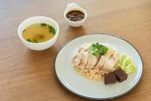 Traditional Singapore chicken rice with salted soybeans sauce and soup on wooden background photo