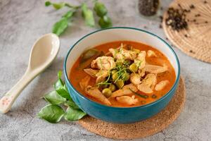 Thai red curry with minced chicken, fresh vegetable and herb in bowl on table, Thai menu and background photo