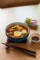 Northern Thai style curried noodle soup with beef and egg on wooden table photo