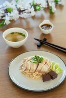 Traditional Singapore chicken rice with salted soybeans sauce and soup on wooden background photo