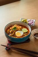 Northern Thai style curried noodle soup with beef and egg on wooden table photo