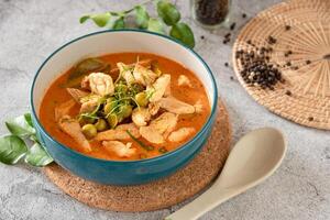 Thai red curry with minced chicken, fresh vegetable and herb in bowl on table, Thai menu and background photo