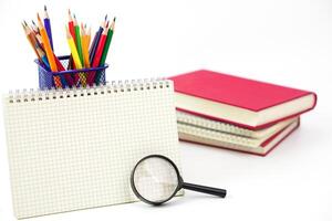 Crayon or colored pencils in box with side stack of books and school supplies on with background. Learning, study and office equipment concept. photo