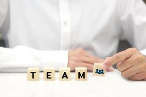 Businessman holding wooden block with text. Teamwork, team management, work in cooperation and business process concept. photo