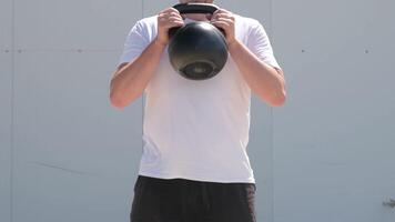 sports and leisure. strong Caucasian man working out using kettlebell in the park, white wall background video