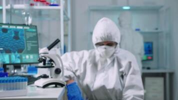Tired doctor wearing coverall looking exhausted at camera in modern equipped lab. Scientist examining virus evolution using high tech and chemistry tools for scientific research, vaccine development. video