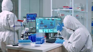 Scientist wearing coverall in equipped medical laboratory examining drug discovery with micropipette. Biochemists analysing virus evolution using high tech researching vaccine against covid19 video