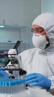 Vertical . Biologist doctor in coverall checking DNA sample typing on pc in modern equipped laboratory. Team examining vaccine evolution in medical lab using high tech and chemistry tools for scientific research video