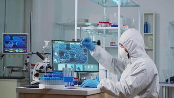 Neurologist with ppe suit working at vaccine development in equipped laboratory typing on pc. Team examining virus evolution using high tech for research in treatment development against covid19 video