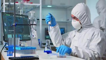 Chemist in ppe suit using micropipette for filling test tubes in modern equipped laboratory. Team of scientists examining virus evolution using high tech for vaccine development against covid19 video