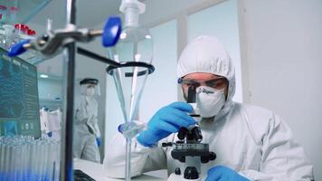 Medical research scientist conducting DNA experiments under microscope wearing protection suit in laboratory. Chemist examining virus evolution using high tech for vaccine development against covid19 video