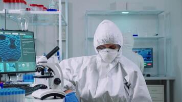 Portrait of overworked biolog looking at camera in modern equipped lab. Team of scientists examining virus evolution using high tech and chemistry tools for scientific research, vaccine development. video