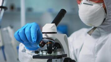 Close up of chemist doctor analysing virus using microscope in ppe suit. Team of scientists examining vaccine evolution using high tech for scientific research of treatment development against covid19 video