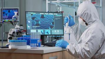Scientist man pipetting liquid to test tube wearing protection suit in lab. Team of doctors examining virus evolution using high tech for scientific analysis of treatment development against covid19 video