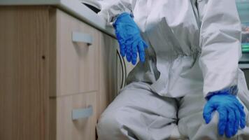 Tired laboratory doctor with overall suit looking at camera in equipped lab. Team of scientists examining virus evolution using high tech, chemistry tools for scientific research, vaccine development video
