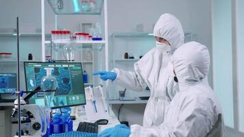 Team of chemists in coverall working to develop vaccine in equipped laboratory. Scientists examining virus evolution using high tech for scientific research of treatment development against covid19 video