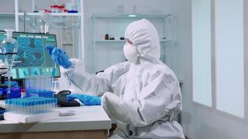 cientista enfermeira dentro ppe terno levando notas em computador olhando às teste tubo dentro laboratório. químicos examinando vacina evolução usando Alto tecnologia para pesquisa dentro tratamento desenvolvimento contra covid19 vírus video
