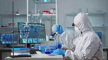 Man scientist in coverall using micropipette in modern equipped laboratory. Team of doctors examining vaccine evolution with high tech and chemistry tools for research in development of covid19 virus video