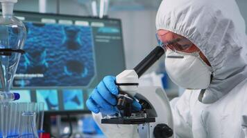 Close up of man scientist looking through a microscope in modern equipped lab. Lab technician examining virus evolution using high tech for scientific research of treatment development against covid19 video