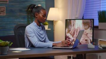 Overworked black entrepreneur working from home late at night on laptop. Tired focused employee using modern technology network wireless doing overtime for job reading writing, searching video