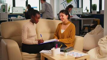 Pleased multiracial business partners sitting on couch in modern office shaking hands after signing partnership contract. Diverse team being happy for successful negotiations in start up company. video