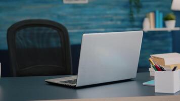 Close up of laptop computer placed on modern working desk in empty home office with blue furniture and walls. Workplace with nobody in it, place of work, workspace concept, pretty simple decor video