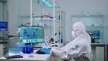 Chemist typing on pc and coworker analysing microscope slides in equipped laboratory. Team of scientists examining vaccine evolution using high tech for researching treatment against covid19 virus video