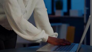 Close up of business african woman smiling at camera after typing on laptop working in startup financial company late at night. Focused employee doing overtime for job respecting deadline of project video