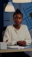 Black manager woman listening partner during conference at midnight from business office planning financial strategy. Lady using modern technology network wireless discussing at virtual meeting video
