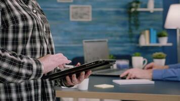 Close up of old woman employee texting, sending and reading messages on tablet during break standing in workplace. Businesswoman using modern technology network wireless overworking in midnight video
