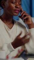 Nervous african manager discussing at smartphone with employee working overtime sitting at desk in business office late at night resolving financial problem. Furious businesswoman overworking video