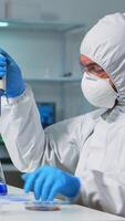 Vertical . Chemist in ppe suit using micropipette for filling test tubes in modern equipped laboratory. Team of scientists examining virus evolution using high tech for vaccine development against covid19 video