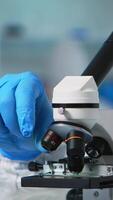 Vertical . Close up of chemist doctor analysing virus using microscope in ppe suit. Team of scientists examining vaccine evolution using high tech for scientific research of treatment development against covid19 video