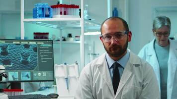 Portrait of exhausted chemist looking at camera in modern equipped lab late at night. Team of biochemists examining virus evolution using high tech and chemistry tool for research, vaccine development video