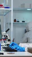Vertical . Scientists in protection suits working in chemical equipped laboratory. Team of biologists examining vaccine evolution using high tech and technology researching treatment against covid19 virus video