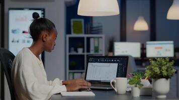 African architect analysing digital plans from laptop working in start-up business office overtime. Designer using cad software to design a 3D concept of buildings creating late at night video