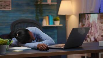 Exhausted overload black businesswoman falling asleep on desk with open laptop monitor while working from home. Busy employee using modern technology network wireless doing overtime sleeping on table. video