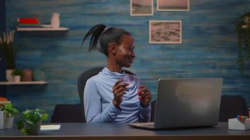 Smiling african american freelancer listening music working on laptop dancing sitting at desk in living room workplace. Black woman enjoy e-learning process, easy application usage overtime. video
