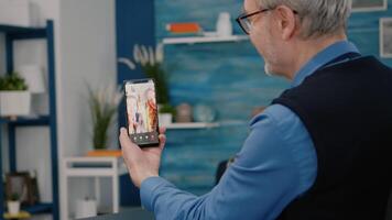 Senior man having call online talk with nephew using smartphone sitting in living room. Retired old person using modern internet online tech to connect with grandparents video