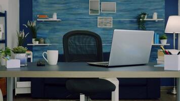 Empty workspace of freelancer worker with laptop computer on desk and cup of coffee. Interior of empty bright workspace with blue furniture and walls, beautiful decorated, cozy apartment video